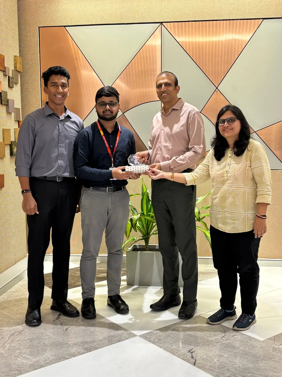 Anshul receiving an award from Hindalco colleagues in an office lobby